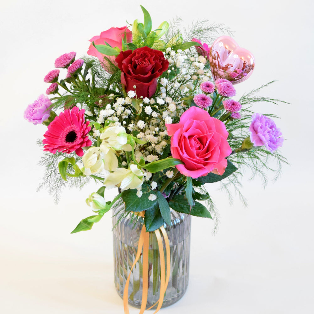 A Vase Of Pink Toned Flowers with a single red rose