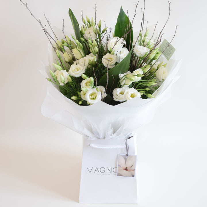 Hampton Hand-Tied Bouquet - Magnolia the Florist Indulge in luxury with our Hampton Hand-Tied Bouquet from Magnolia the Florist. Our skilled florists expertly hand-tie lisianthus and lush foliage, creating a truly exquisite bouquet. Presented in our signature hand-tied bag, this bouquet is the perfect combination of elegance and sophistication.