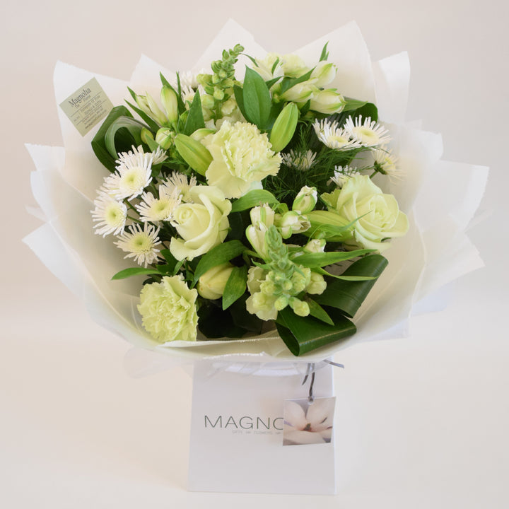 Kensington Hand-Tied Bouquet - Magnolia the Florist Crafted by our skilled florists, the Kensington Hand-Tied Bouquet from Magnolia the Florist, features a stunning combination of white flowers with a hint of green, including roses, alstroemeria, antirrhinums, chrysanthemum, carnation, lily, and foliage. Perfect for any occasion, this bouquet offers a gorgeous display of beauty and elegance.