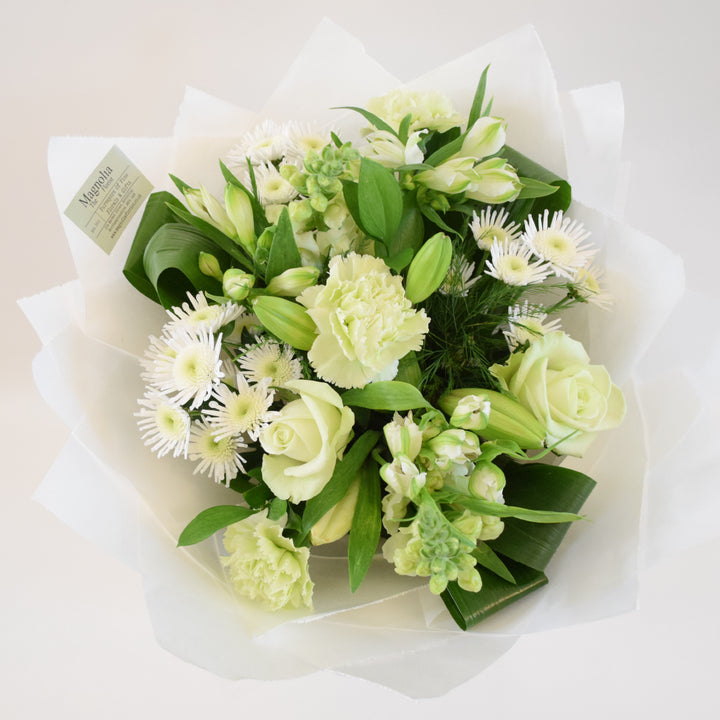 Kensington Hand-Tied Bouquet - Magnolia the Florist Crafted by our skilled florists, the Kensington Hand-Tied Bouquet from Magnolia the Florist, features a stunning combination of white flowers with a hint of green, including roses, alstroemeria, antirrhinums, chrysanthemum, carnation, lily, and foliage. Perfect for any occasion, this bouquet offers a gorgeous display of beauty and elegance.