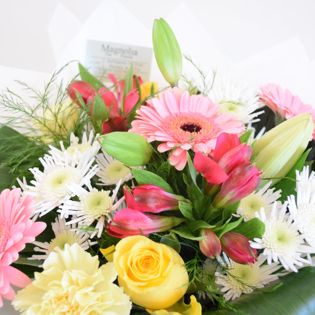 St James Hand-Tied Bouquet - Magnolia the Florist Indulge in luxury with the St James hand-tied bouquet from Magnolia the Florist. A stunning arrangement of lilies, roses, chrysanthemums, carnations, alstroemeria, and mini gerbera in white, yellow, and pink tones. Expertly hand-tied and presented in our elegant box bag, this bouquet is sure to impress.